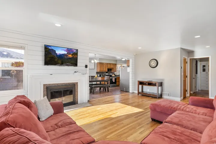 Living area featuring wood-finish flooring, recessed lighting, and a white shiplap accent wall