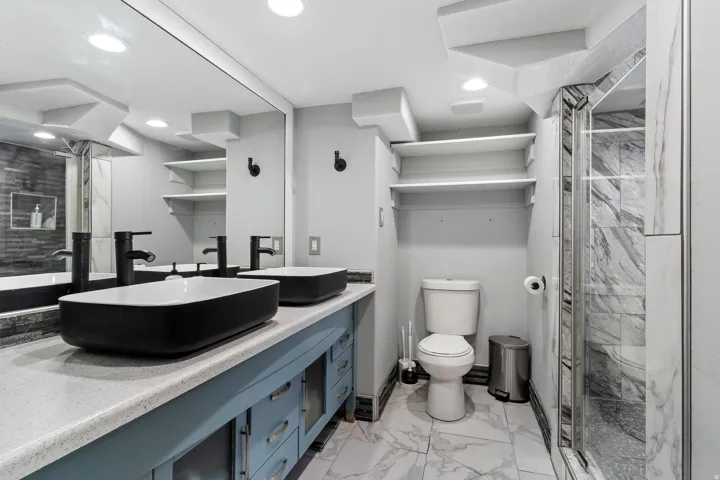 Contemporary bathroom featuring a double vanity with vessel sinks, light-toned countertop, and blue cabinetry