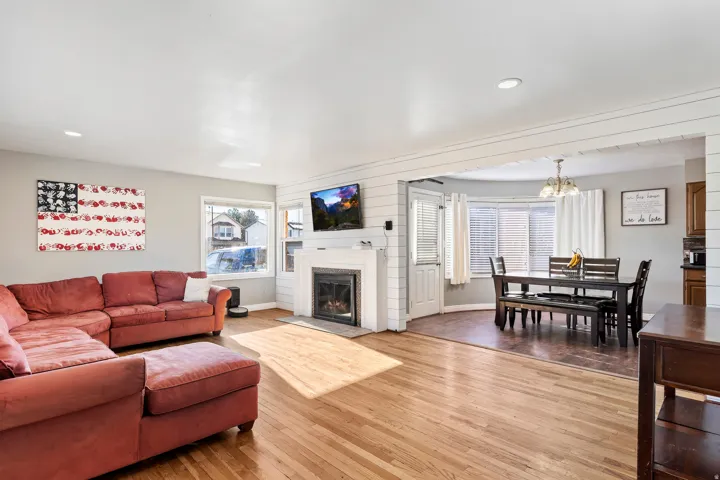 Open-concept living area featuring wood-finish flooring, recessed lighting, and a white brick fireplace