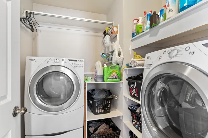Dedicated laundry area featuring a front-loading washer and dryer, built-in shelving, and a hanging rod