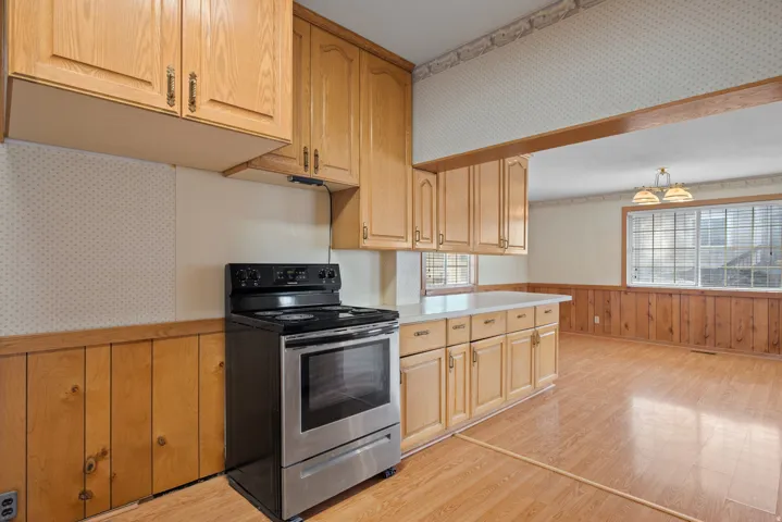 Kitchen featuring wood-finish cabinetry, stainless steel range, and light-colored countertops