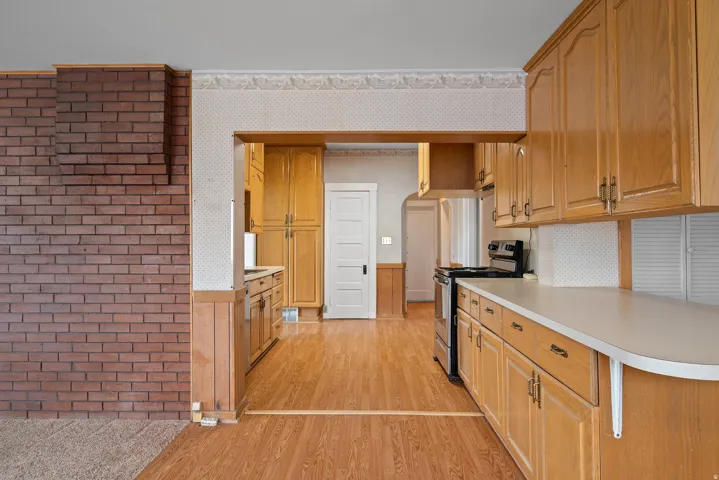 Kitchen featuring wood-finish flooring, wood cabinetry, white countertops, and a stainless steel range