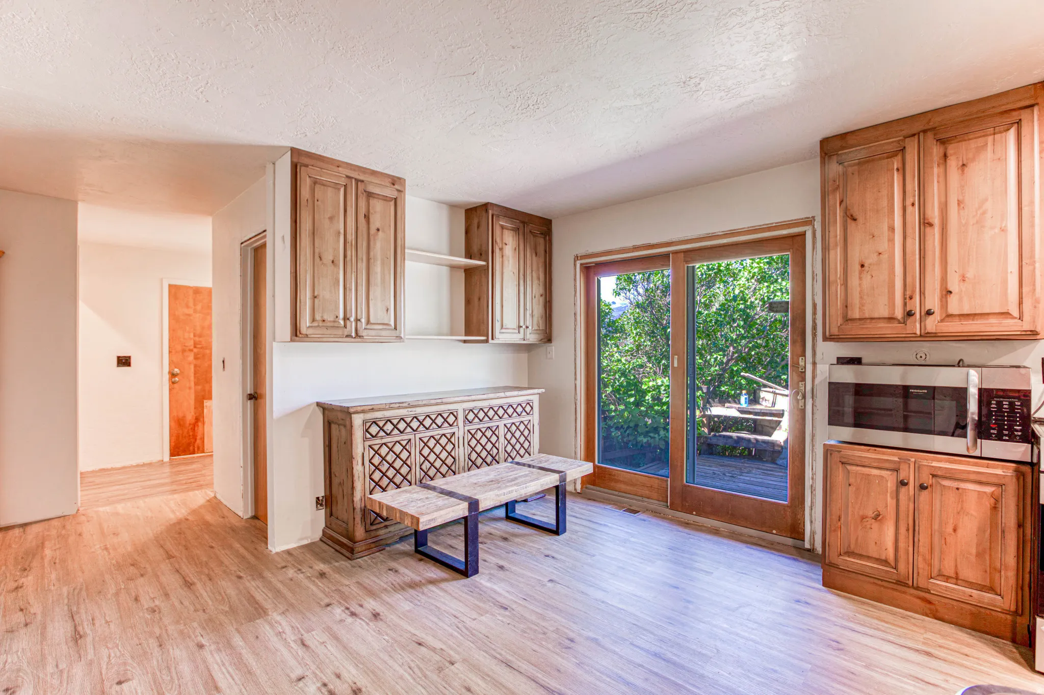 Kitchen area with wood-finish flooring, natural wood cabinetry, and a built-in microwave