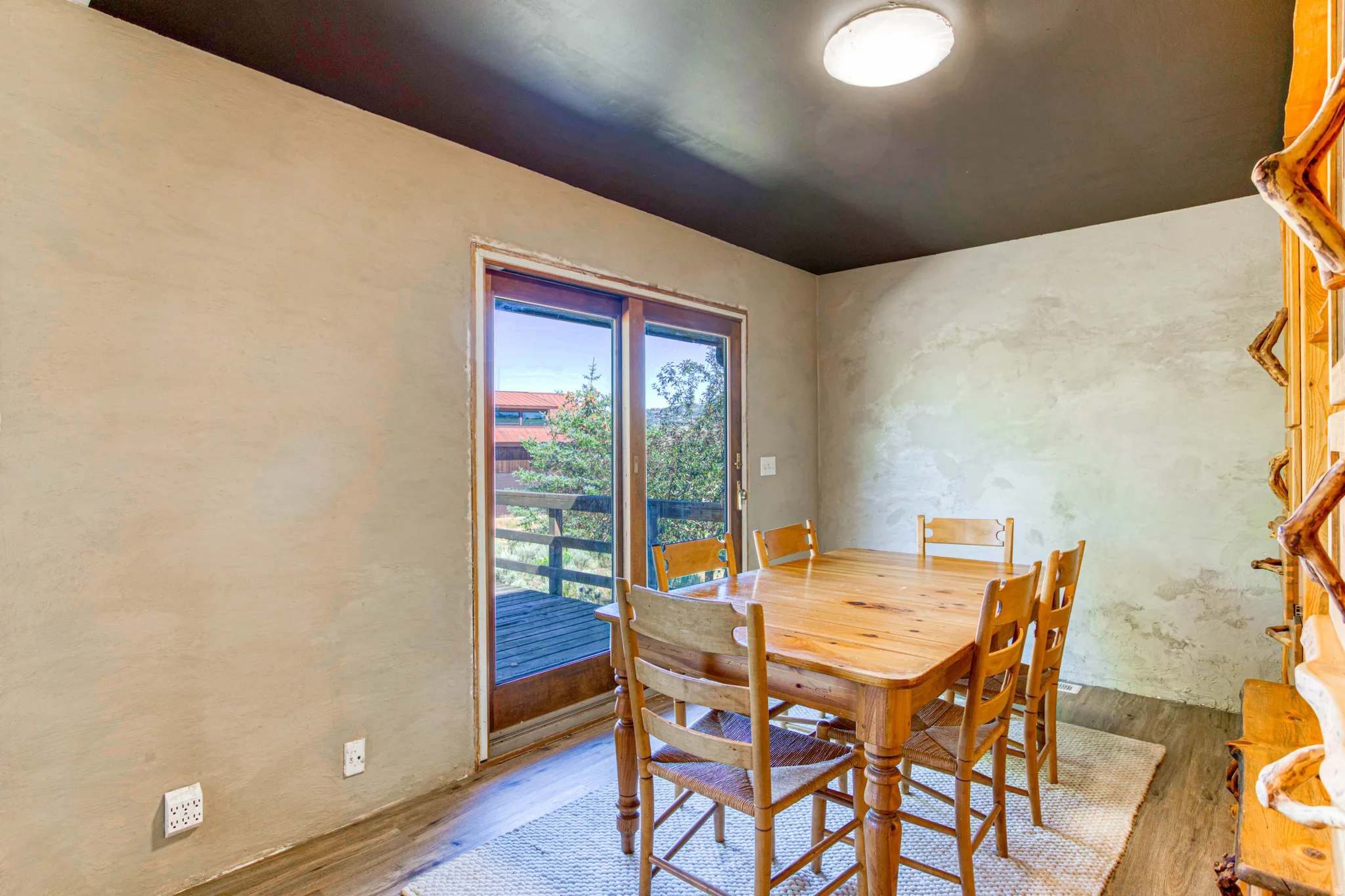 Dining area featuring wood-finish flooring, textured wall finishes, and a dark ceiling with a flush-mount light fixture