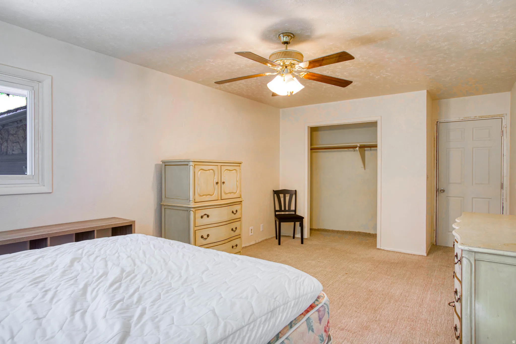 Room featuring neutral wall tones, textured ceiling, a ceiling fan with integrated lighting, and light-toned carpeting