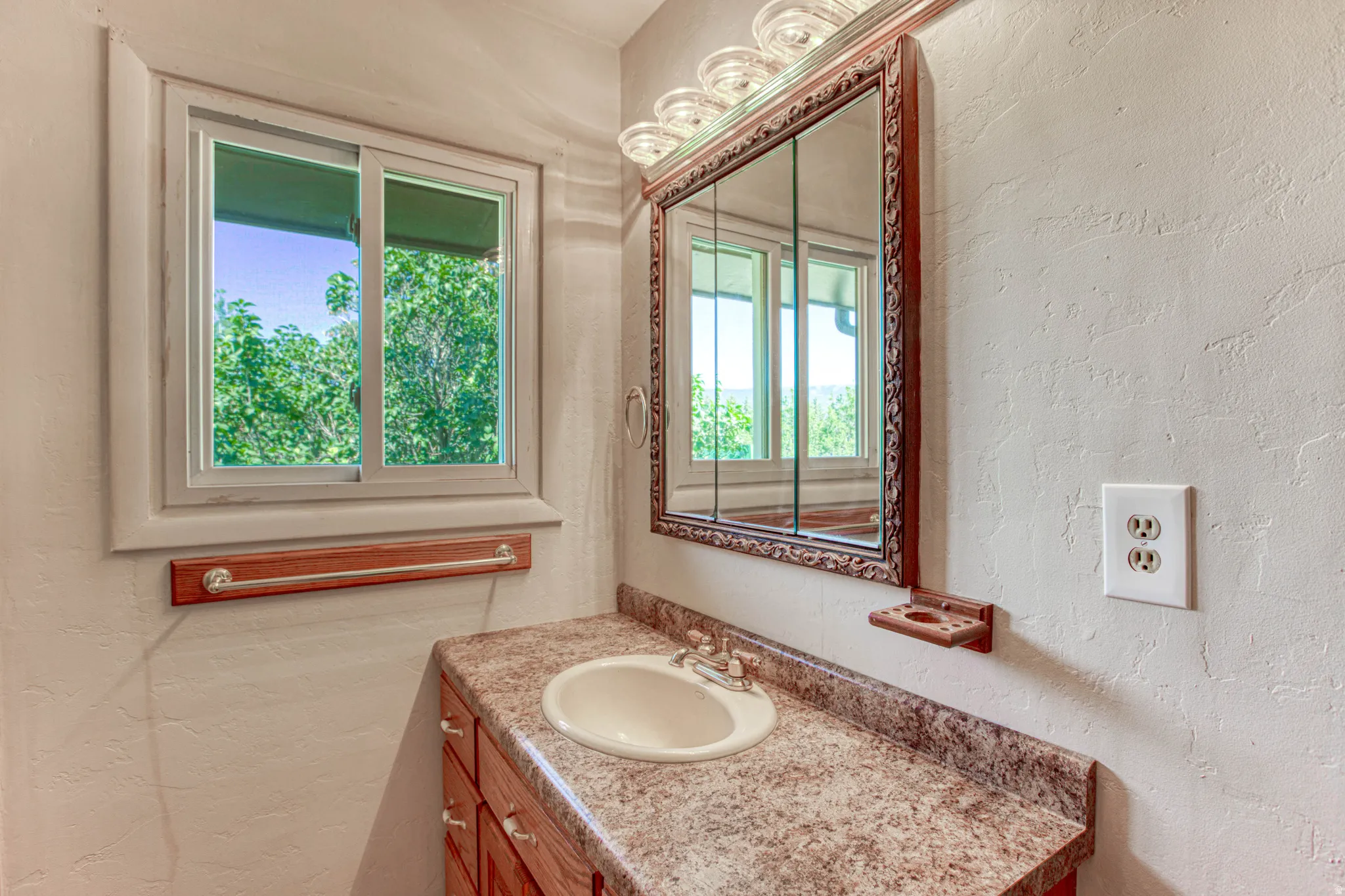 Bathroom vanity featuring an integrated sink, laminate countertop, and wood-finish cabinetry