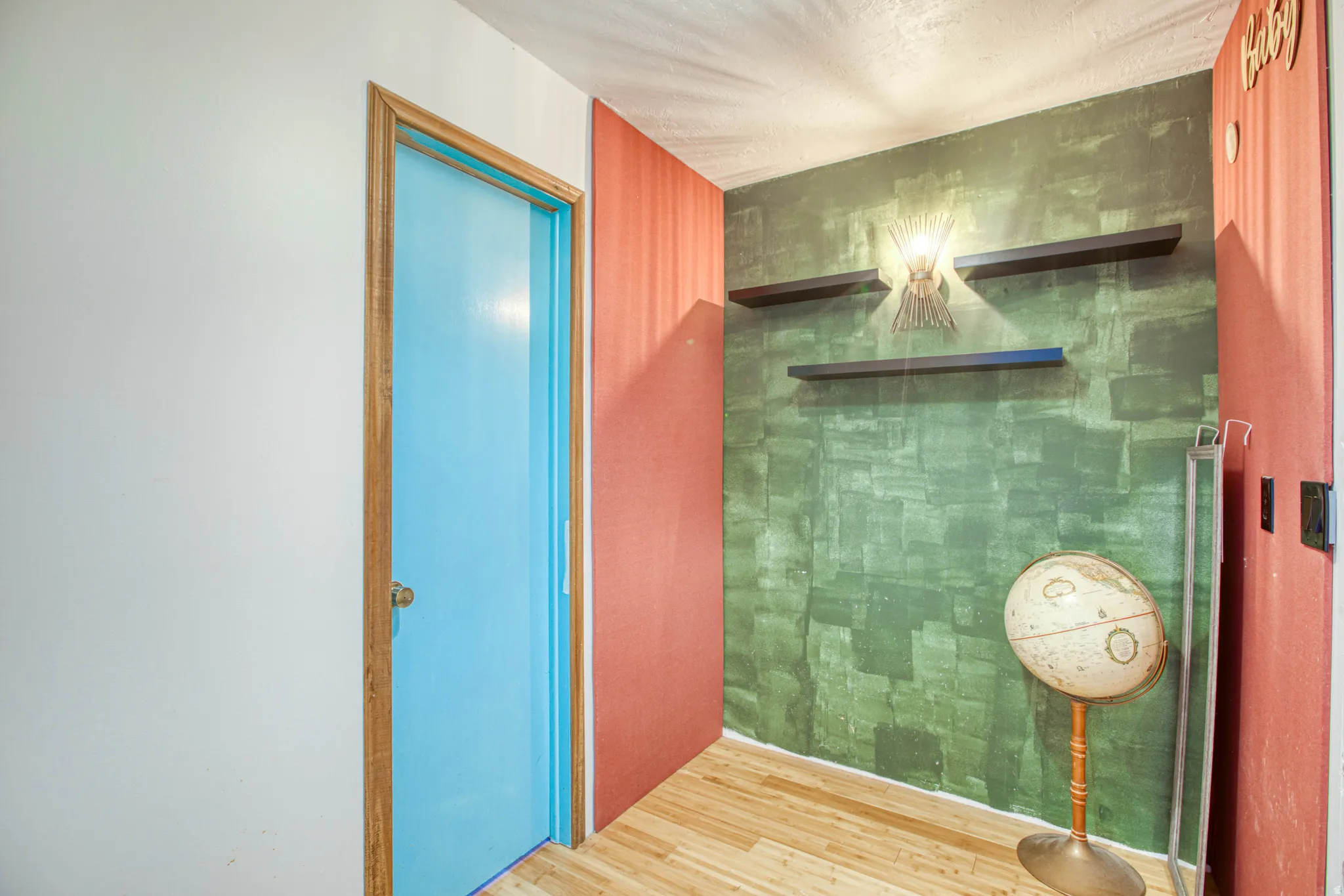 Accent wall featuring a textured green finish, complemented by two floating shelves