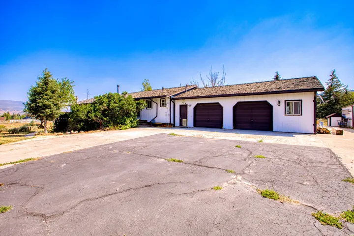 White exterior with brown trim, two-car garage with arched doors, and a shingled roof