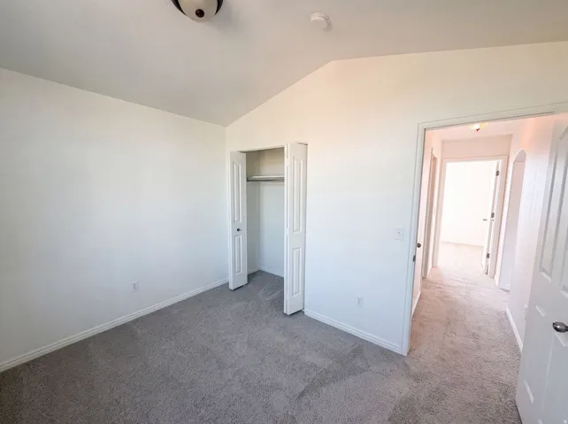 Room with light gray carpeting, white walls, and a built-in closet with bi-fold doors