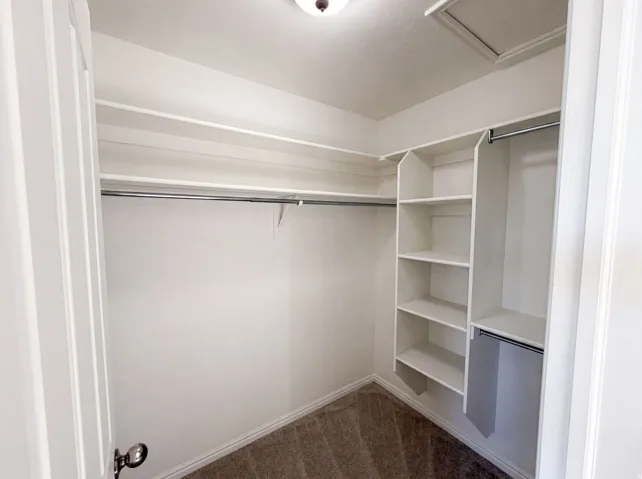 Walk-in closet featuring built-in shelving, multiple hanging rods, and neutral-toned carpeting