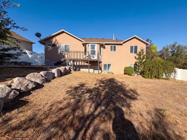 Terraced backyard with a rock retaining wall, featuring a raised deck with dark railings, and a walk-out basement