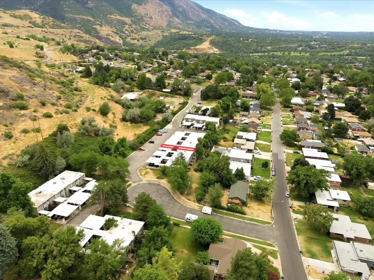 Aerial perspective showcasing multi-unit residential buildings with carports, surrounded by mature trees and a residential neighborhood