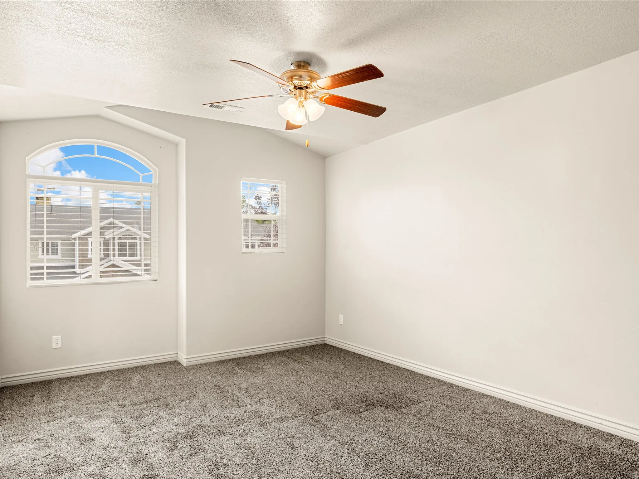 Room featuring an arched window, a secondary window, and a ceiling fan with light fixture