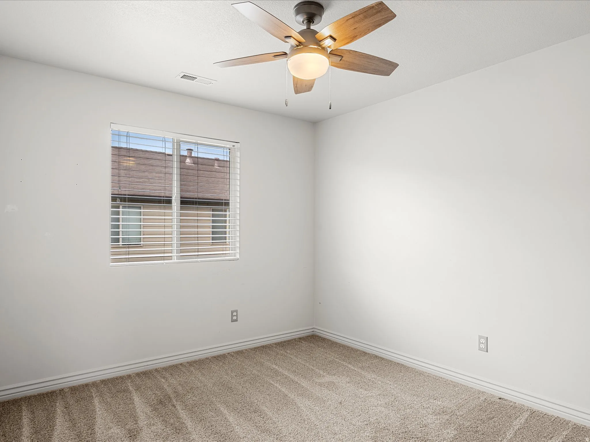 Carpeted room featuring a ceiling fan with light fixture, window with horizontal blinds, and white baseboard trim