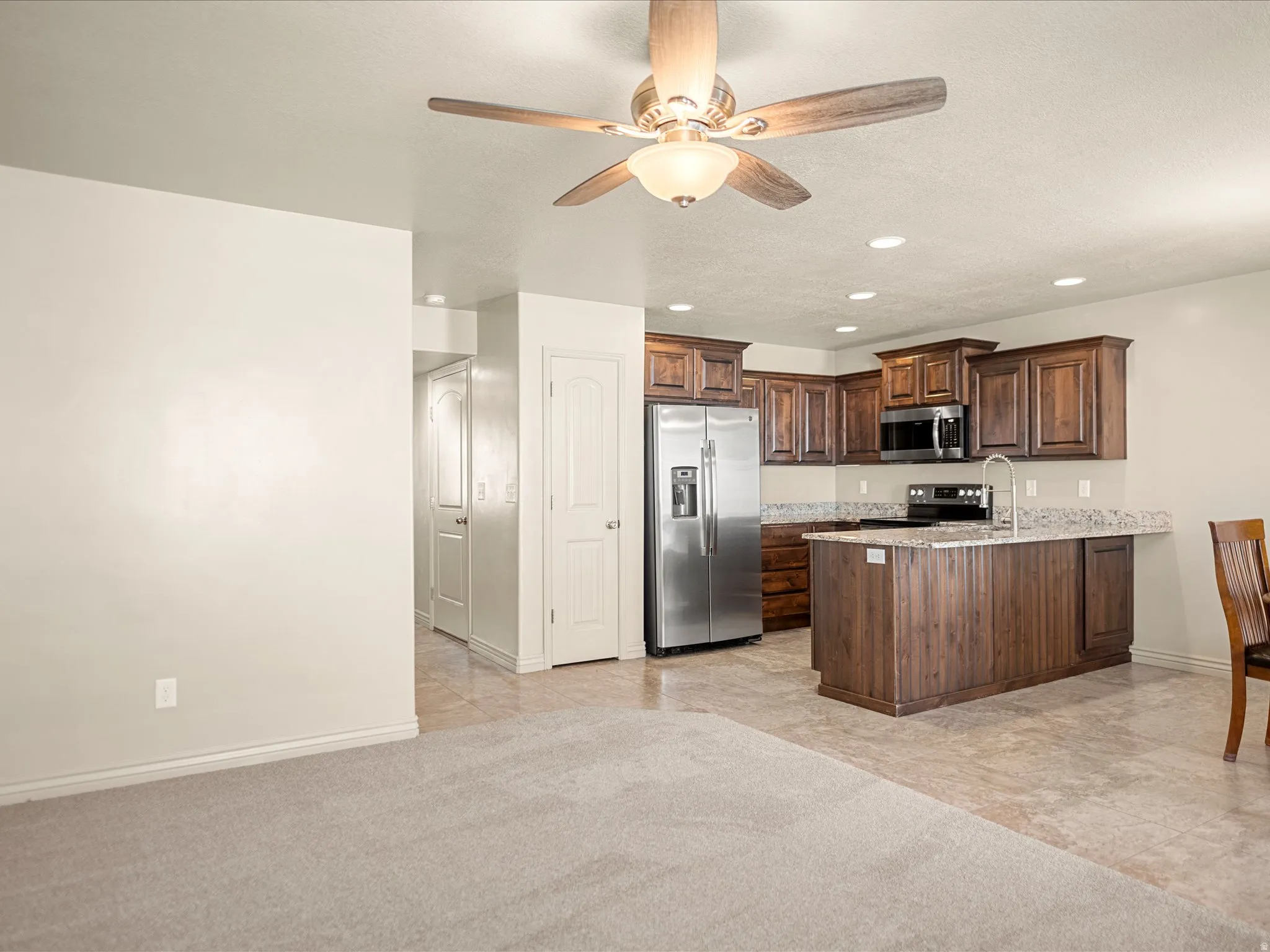 Kitchen featuring dark wood cabinetry, stainless steel appliances, and a central island with a granite-style countertop