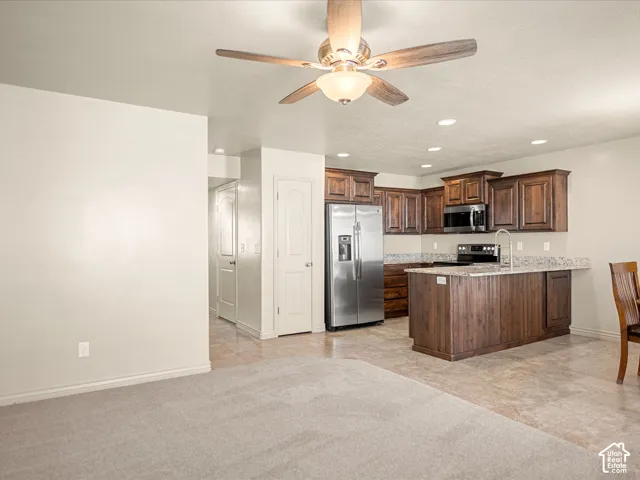 Kitchen featuring dark wood cabinetry, stainless steel appliances, and a central island with a granite-style countertop