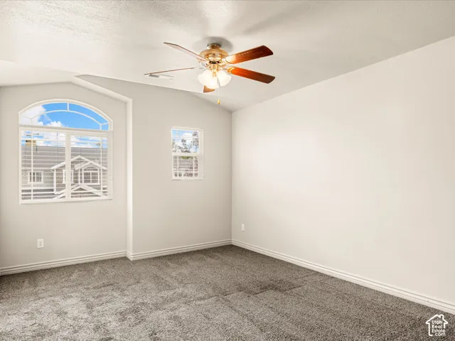 Room featuring an arched window, a secondary window, and a ceiling fan with light fixture