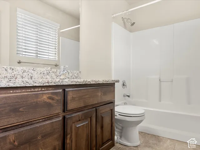 Bathroom featuring a dark wood-finish vanity with a speckled countertop, a white toilet, and a white shower-over-tub combination with chrome fixtures