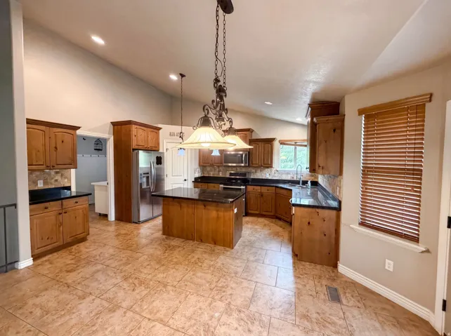 Kitchen featuring an expansive tiled floor, wood cabinetry, dark countertops, and a central island