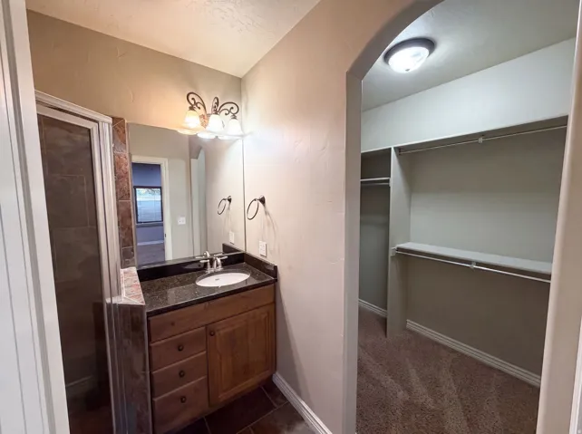 Bathroom featuring a dark wood vanity with a stone countertop and an undermount sink
