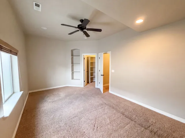 Carpeted room featuring a ceiling fan with light, recessed lighting, a built-in arched alcove with shelving, and a window with blinds
