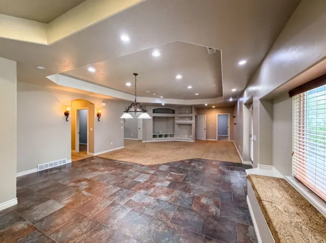 Expansive living area featuring multi-tone tile flooring, recessed lighting, and a tray ceiling with cove lighting