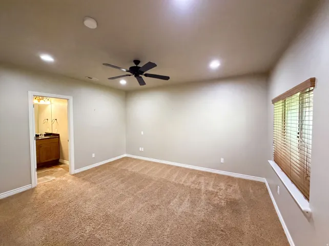 Spacious room featuring neutral carpeting, recessed lighting, and a ceiling fan