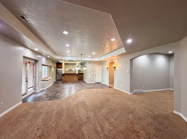 Expansive open-concept space featuring recessed ceiling lighting, a built-in window seat, and a combination of carpet and tile flooring