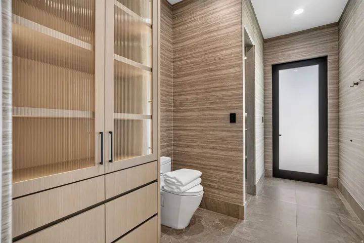 Integrated light wood-finish cabinetry featuring fluted glass panels and matte black hardware