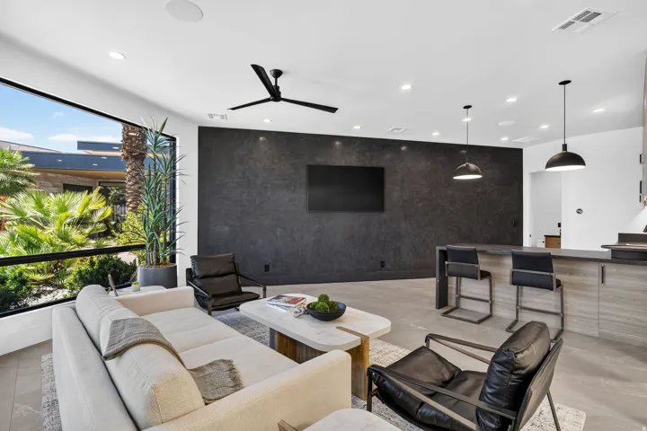 Open-concept living area featuring a large picture window, a textured accent wall, recessed lighting, and a modern ceiling fan