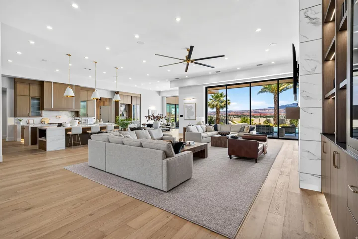 Open-concept living space featuring wood-finish flooring, a large area rug, and a modern ceiling fan