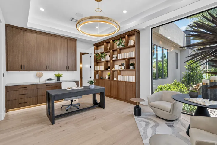 Dedicated workspace featuring built-in wood-finish cabinetry, integrated shelving, a recessed ceiling, and large floor-to-ceiling windows