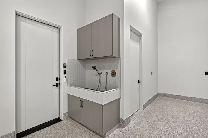 Dedicated utility area featuring a built-in wash station with a handheld sprayer, overhead cabinetry, and lower storage