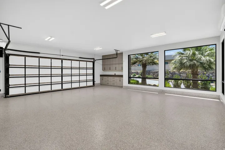 Spacious garage featuring a glass-paneled sectional door, epoxy-coated flooring, and large windows