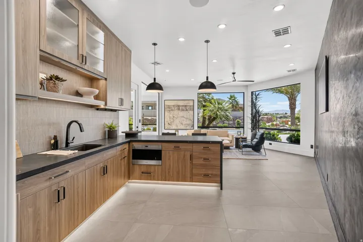 Contemporary kitchen featuring wood-finish cabinetry with frosted glass accents, dark countertops, and a built-in oven
