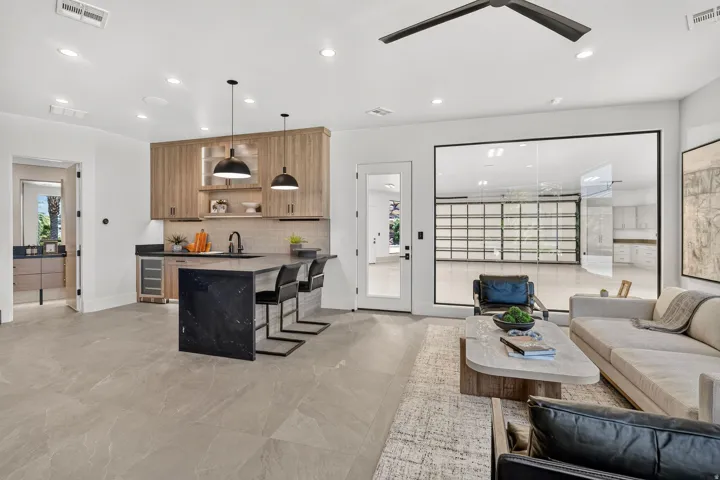 Spacious interior featuring large format tile flooring and a built-in wet bar with wood cabinetry and dark stone countertops
