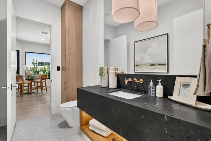 Modern vanity with a dark stone countertop and integrated sink, featuring a wall-mounted brass faucet