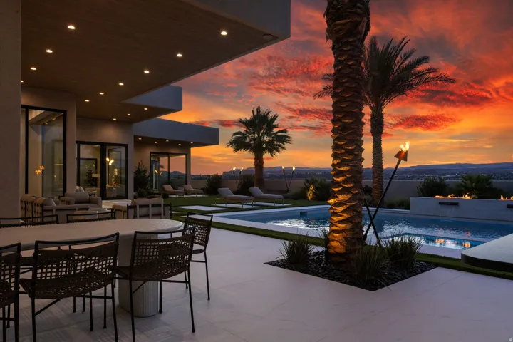 Expansive exterior patio featuring a built-in swimming pool, integrated fire feature, and mature palm trees