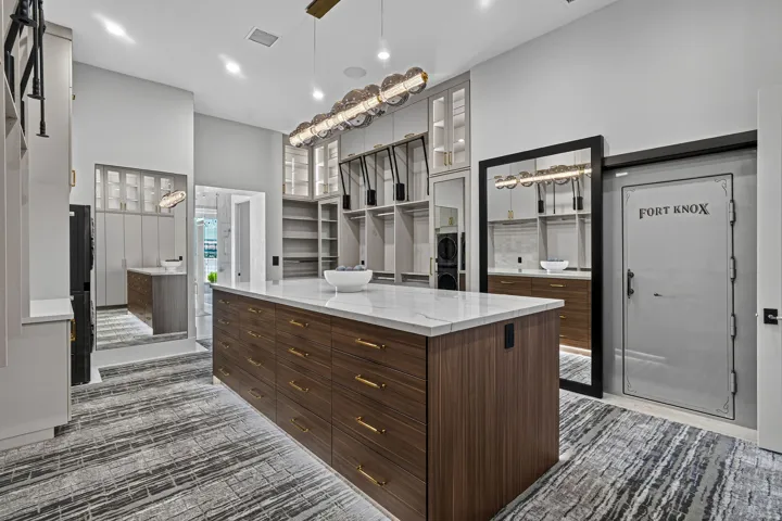 Spacious custom closet featuring a large central island with a stone countertop and wood-finish cabinetry