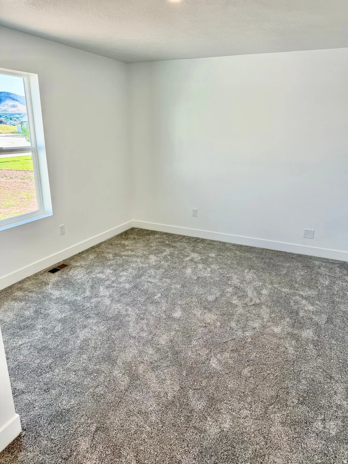 Spacious room featuring neutral carpeting and white baseboards