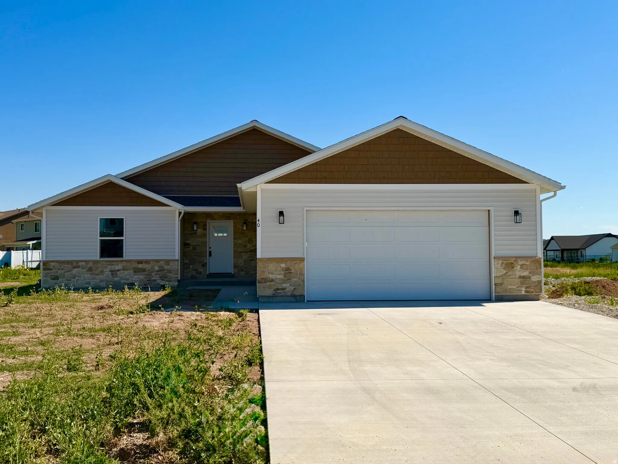 Contemporary single-story home featuring a two-car garage, stone and siding exterior, and a concrete driveway