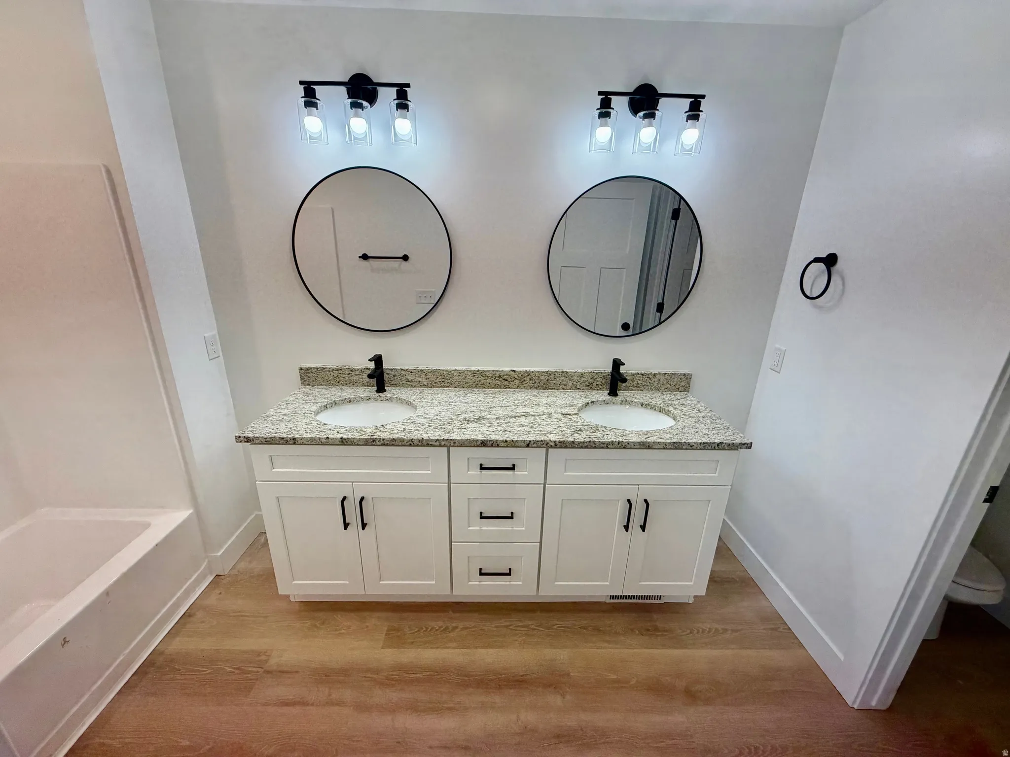 Bathroom featuring a dual vanity with granite countertops, undermount sinks, and matte black fixtures