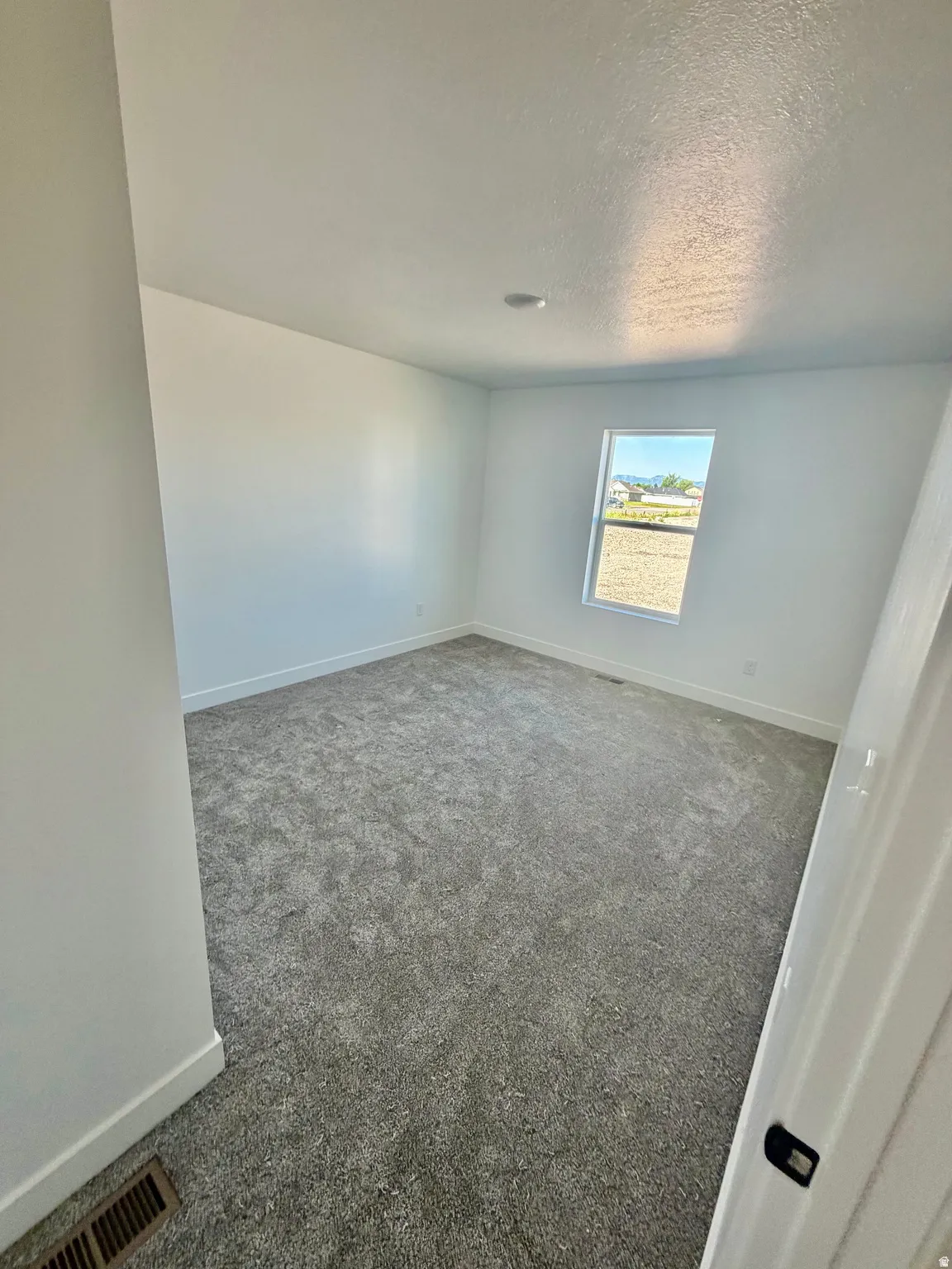 Spacious room featuring neutral carpeting, white walls, a single window, and a recessed ceiling light