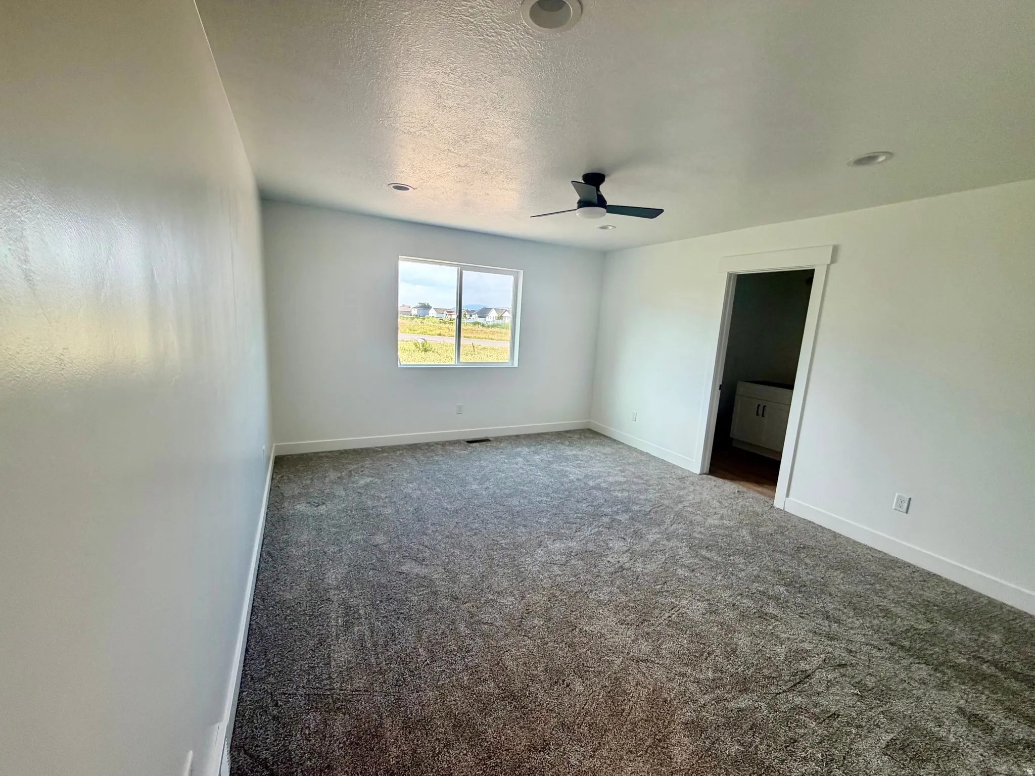 Carpeted interior room with white walls, a single window, and recessed lighting