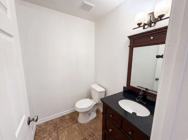 Bathroom featuring a dark wood vanity with a framed mirror, a black countertop, and an undermount sink with a black faucet