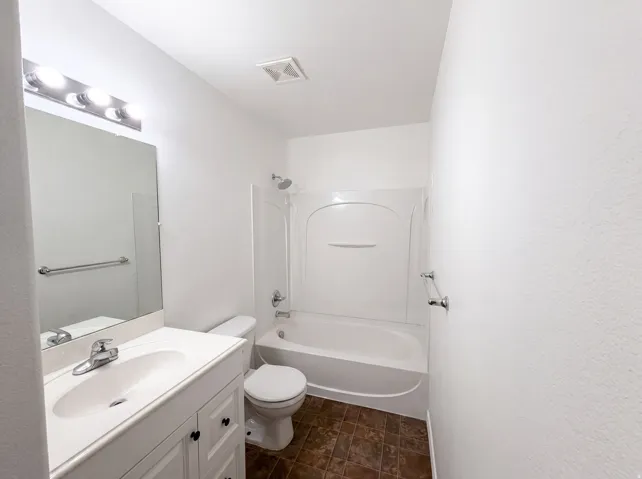 Bathroom featuring a white vanity with integrated sink, chrome faucet, and a large mirror