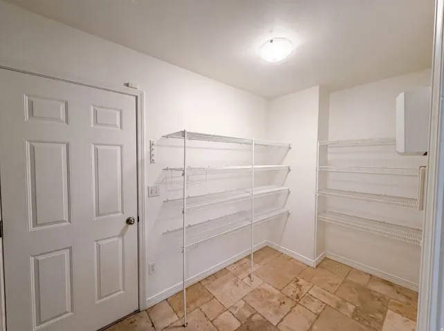 Utility room with tile flooring and multiple white wire shelving units