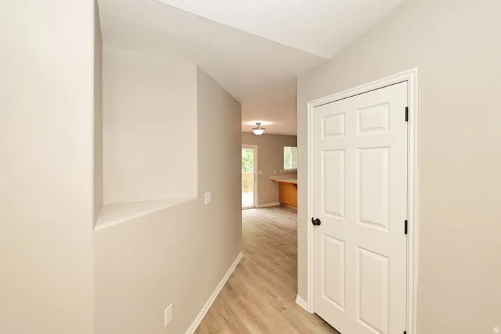 Entryway featuring wood-finish flooring, light neutral wall paint, white trim, and a white six-panel door with matte black hardware