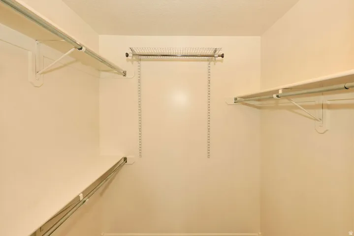 Walk-in closet featuring light beige walls and a textured ceiling