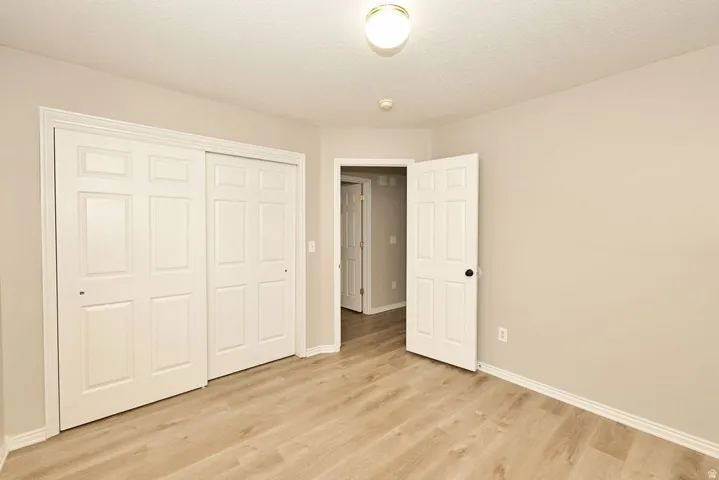 Room featuring wood-finish flooring, neutral wall paint, and white baseboards
